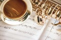 Romantic morning. Close up view of saxophone and cup of coffee lying on the musical notes.