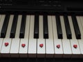 Romantic music, a piece of piano, white and black keys with small red hearts Royalty Free Stock Photo