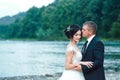 Romantic newlywed couple hugging near blue lake, sensual groom embracing gorgeous bride from behind near river. Wedding day for ma Royalty Free Stock Photo