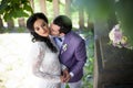 Romantic newlywed couple kissing under tree, bouquet on stairs Royalty Free Stock Photo