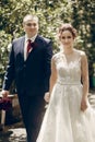 Romantic newlywed couple walking in the park, handsome groom and happy beautiful bride with bouquet holding hands close-up in Royalty Free Stock Photo