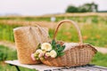 Outdoor image of straw bag and basket full of freshly cut roses
