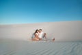 Romantic pair sit on white sand and huggins, in desert