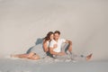 Romantic pair sit on white sand and huggins, in desert