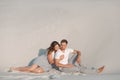 Romantic pair sit on white sand and huggins, in desert