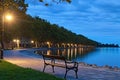 Romantic and peaceful scene. Empty bench illuminated by lamppost. Morning landscape view of Lake Balaton and Plane tree alley