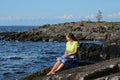 Romantic photo of a girl sitting on the rocks by lake on a sunny day