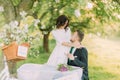 Romantic picknick in park. Playful bride hugging her lovely new husband while he drinks tea Royalty Free Stock Photo