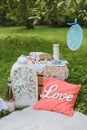 Romantic picnic decor for two: a pillow, a bottle of wine, a white lantern, books and candles on a blanket