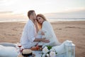 Romantic picnic at sunset. couple is sitting on blanket. Man gently hugs pregnant woman. She looks into the distance. Royalty Free Stock Photo
