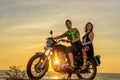 Romantic picture with a couple of beautiful stylish bikers at sunset. Handsome guy with tatoo and young sexy woman enjoy