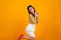 Romantic pinup girl dancing on yellow background. Studio shot of playful young lady in white skirt Royalty Free Stock Photo