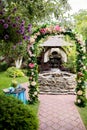 Romantic place with floral arch and fountain made in stones in the garden Royalty Free Stock Photo