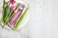 Romantic place setting for spring holiday, valentines day; fork and knife, bouquet of pink tulips on the napkin top view Royalty Free Stock Photo