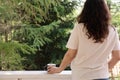 A romantic portrait of a beautiful young woman in a T-shirt and jeans, resting on a balcony overlooking the forest, with Royalty Free Stock Photo