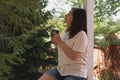 A romantic portrait of a beautiful young woman in a T-shirt and jeans, resting on a balcony overlooking the forest, with Royalty Free Stock Photo