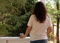 A romantic portrait of a beautiful young woman in a T-shirt and jeans, resting on a balcony overlooking the forest, with Royalty Free Stock Photo