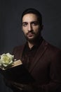 Romantic. Portrait of a guy. In the hands of a book and a white flower. The guy in the brown suit. Royalty Free Stock Photo