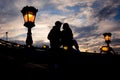 Romantic portrait of the loving couple silhouette sitting on the Chain Bridge near the lightning street lamp in Budapest