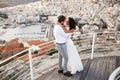 Romantic portrait of two beautiful young couple, poses in wedding clothing, behind town in Greece, during summer sunset. Royalty Free Stock Photo