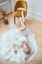 Romantic portrait of a woman on the floor in a beautiful long white dress. The girl is blonde with blue eyes and beautiful makeup Royalty Free Stock Photo