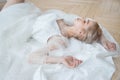 Romantic portrait of a woman on the floor in a beautiful long white dress. The girl is blonde with blue eyes and beautiful makeup Royalty Free Stock Photo