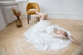 Romantic portrait of a woman on the floor in a beautiful long white dress. The girl is blonde with blue eyes and beautiful makeup Royalty Free Stock Photo