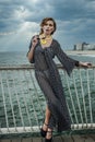 Romantic portrait of young woman wearing black and white dress on the pier.