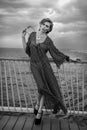 Romantic portrait of young woman wearing black and white dress posing on the pier. Royalty Free Stock Photo