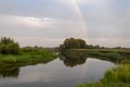 A romantic rainbow against the background of a clear morning sky over a quiet river