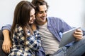 Romantic relaxed young couple using tablet computer on sofa at home Royalty Free Stock Photo