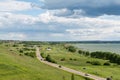 Romantic road into the distance, horizon, lake and green flat plain. Royalty Free Stock Photo