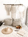 Romantic scandi boho style bedroom interior with wicker hat, fresh fruits and open book on bed