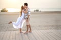 Romantic scene of beautiful young pregnant couple embraced on the beach at sunset. Royalty Free Stock Photo