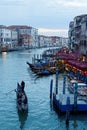 Romantic scenery of tourists riding in a gondola on Grand Canal at sunset, with ferry boats parking by restaurants & bars