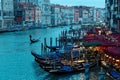 Romantic scenery of tourists riding in a gondola on Grand Canal at sunset, with ferry boats parking by restaurants & bars