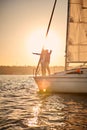 Romantic senior couple enjoying sailing together at sunset, stretching hands out against the sky while standing on the Royalty Free Stock Photo