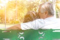 Romantic senior couple. Grandfather embracing, kissing grandmother. Lovely elderly couple sitting on bench at park. Elderly man an