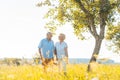 Romantic senior couple holding hands while walking together in a field Royalty Free Stock Photo