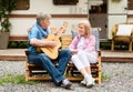 Romantic senior man playing guitar and singing song to his wife near camper van in countryside Royalty Free Stock Photo
