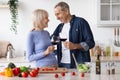 Romantic senior spouses drinking wine while cooking together Royalty Free Stock Photo
