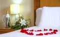 Romantic setup with honeymoon bed with focus on the bouquet and champagne bottle and flute Royalty Free Stock Photo