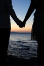Romantic silhouette couple holding hands on a beach in sunset. Royalty Free Stock Photo