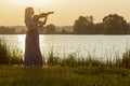 Romantic Silhouette Of Young Woman With A Violin At Dawn On River Bank, Elegant Girl Playing A Musical Instrument On Nature,