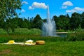 A romantic sitting with a covers and cozy cushions and pillows in a park with a background of a lake with a fountain and tress on