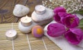 Romantic spa with bath bomb, tulips, candles and pebbles on wooden background.