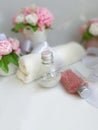 Romantic spa concept. Cosmetic pearl bottles, towel, bouquet of soap flowers on white background. Royalty Free Stock Photo