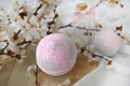 Romantic spa cosmetic composition. Close up bath bombs, blossom branch on light background.