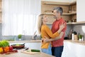 Romantic spouses embracing while preparing meal together at home