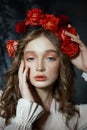 Romantic spring portrait of a young blonde woman with a wreath of red rose flowers, a girl in a light white dress. A woman with Royalty Free Stock Photo